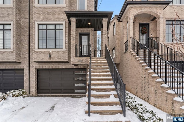 snow covered property entrance featuring a garage