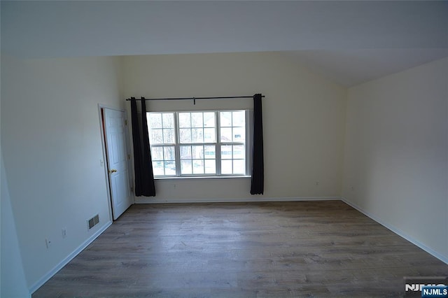 spare room with vaulted ceiling and dark hardwood / wood-style flooring