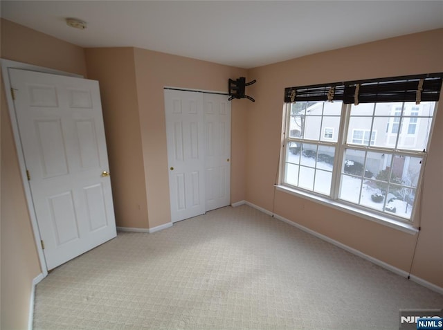 unfurnished bedroom with light colored carpet and a closet