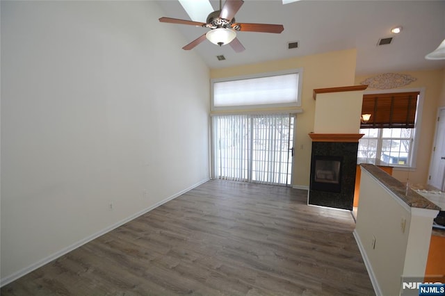 unfurnished living room featuring a tiled fireplace, dark hardwood / wood-style flooring, high vaulted ceiling, and ceiling fan