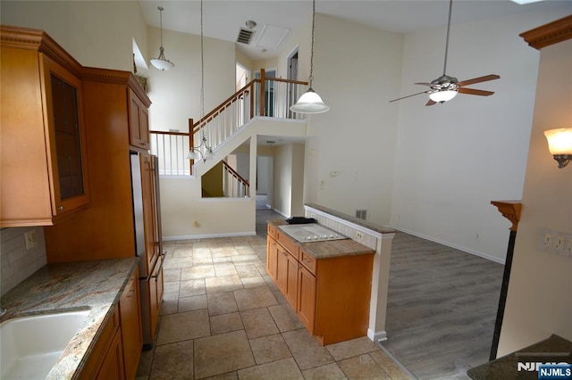 kitchen with sink, hanging light fixtures, paneled fridge, ceiling fan, and backsplash