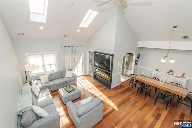 living room featuring hardwood / wood-style flooring, ceiling fan with notable chandelier, and high vaulted ceiling