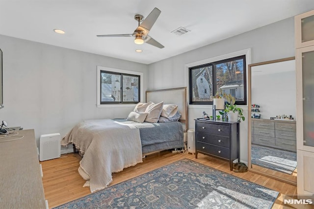 bedroom featuring multiple windows, wood-type flooring, and ceiling fan