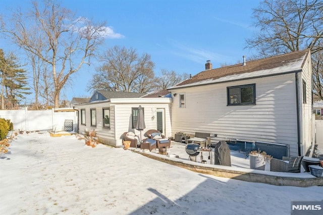 snow covered rear of property with a fire pit