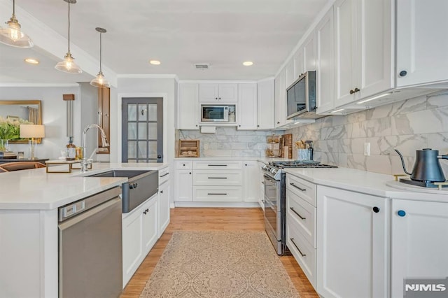 kitchen featuring pendant lighting, sink, stainless steel appliances, and white cabinets