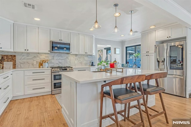 kitchen with stainless steel appliances, a breakfast bar, a kitchen island, and white cabinets