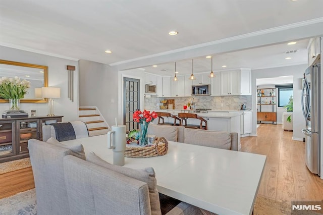 dining room with crown molding and light wood-type flooring