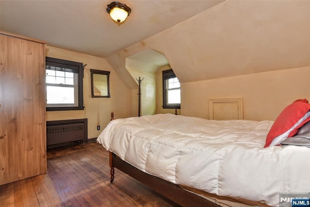 bedroom with vaulted ceiling, radiator, and dark wood-type flooring