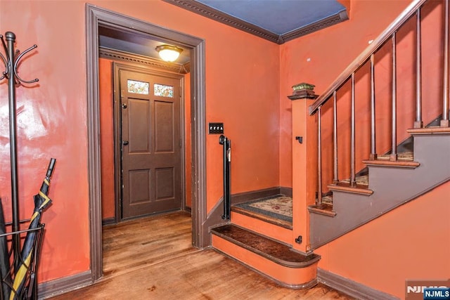 entryway with ornamental molding and light hardwood / wood-style floors