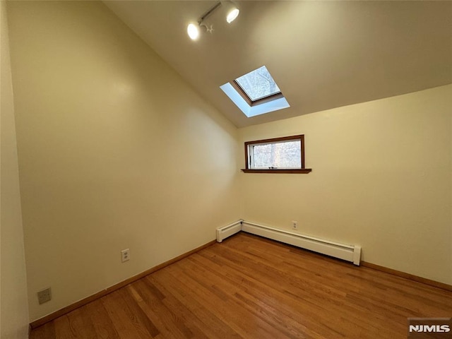 additional living space with baseboard heating, wood-type flooring, and vaulted ceiling with skylight