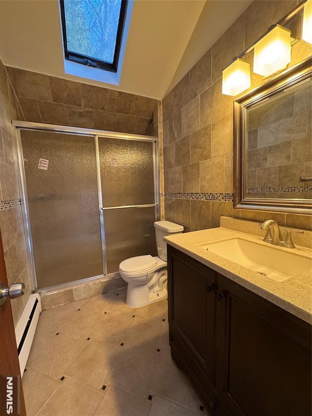 bathroom with tile walls, vaulted ceiling with skylight, vanity, a baseboard radiator, and toilet