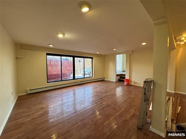 unfurnished room with dark hardwood / wood-style flooring and a baseboard heating unit