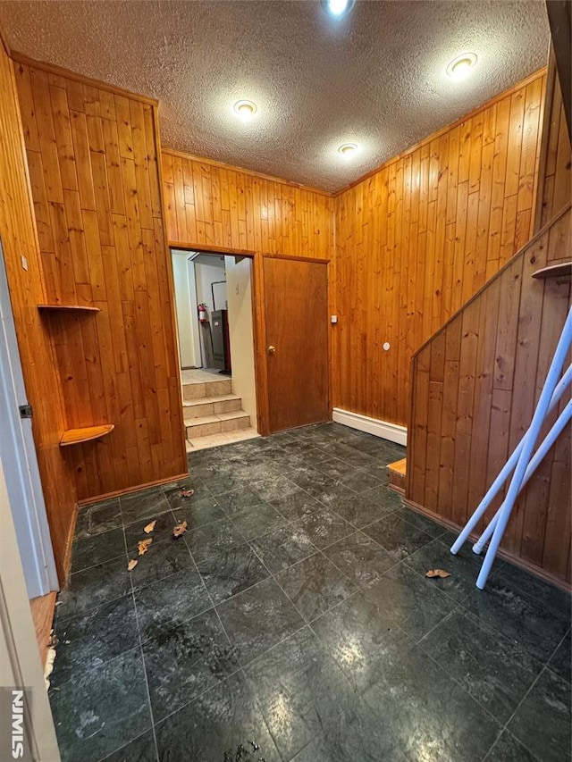 interior space featuring wood walls, a textured ceiling, and baseboard heating