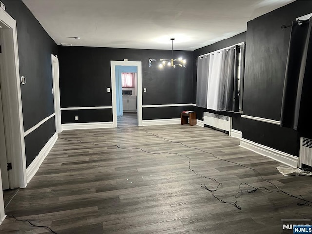 unfurnished dining area featuring radiator, wood-type flooring, and a chandelier