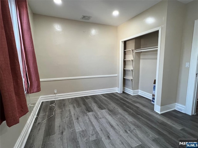 unfurnished bedroom featuring dark hardwood / wood-style flooring and a closet