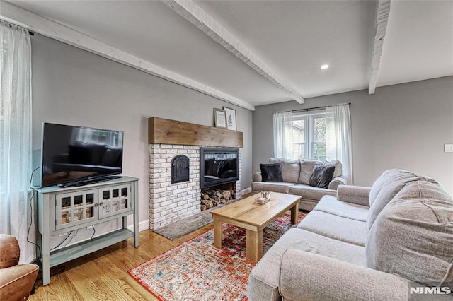 living room with beamed ceiling, wood-type flooring, and a brick fireplace