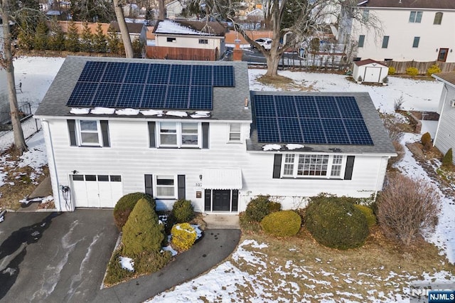 view of front facade with solar panels and a storage shed