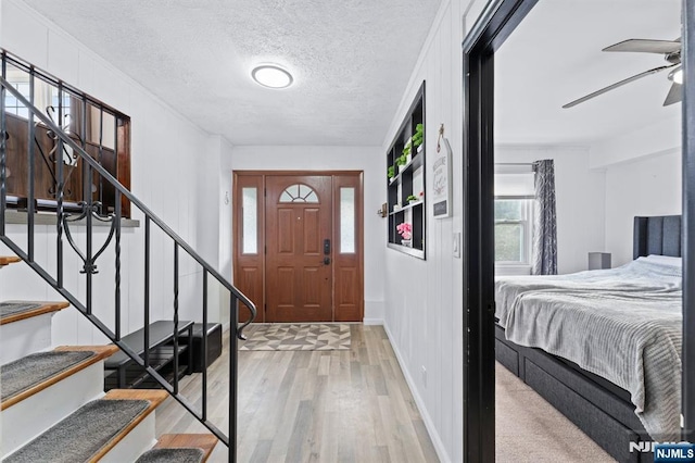 foyer entrance featuring ceiling fan, light wood-type flooring, and a textured ceiling