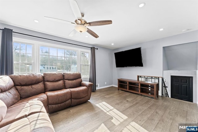 living room with light hardwood / wood-style floors, ceiling fan, and a healthy amount of sunlight