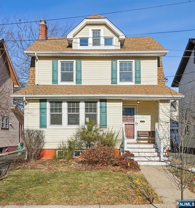 traditional style home featuring a front lawn, a chimney, and a shingled roof