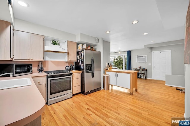 kitchen featuring appliances with stainless steel finishes, sink, light wood-type flooring, light brown cabinets, and a wall unit AC