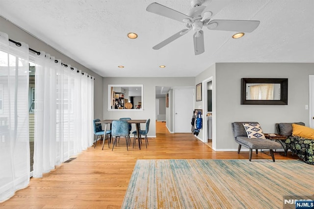 sitting room featuring ceiling fan, light hardwood / wood-style floors, and a textured ceiling