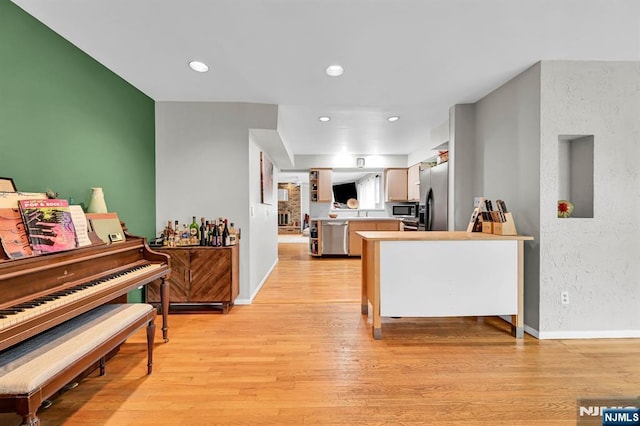 kitchen with light hardwood / wood-style flooring, kitchen peninsula, white cabinets, and appliances with stainless steel finishes