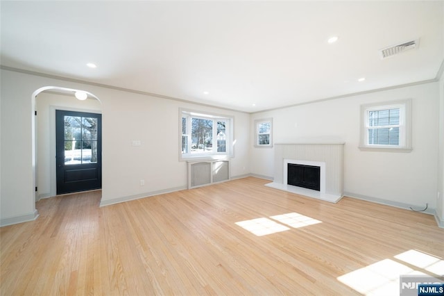 unfurnished living room with ornamental molding, a healthy amount of sunlight, and light hardwood / wood-style flooring