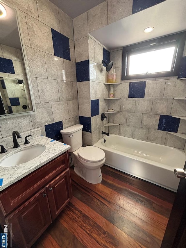 full bathroom featuring tile walls, tiled shower / bath combo, vanity, hardwood / wood-style flooring, and toilet