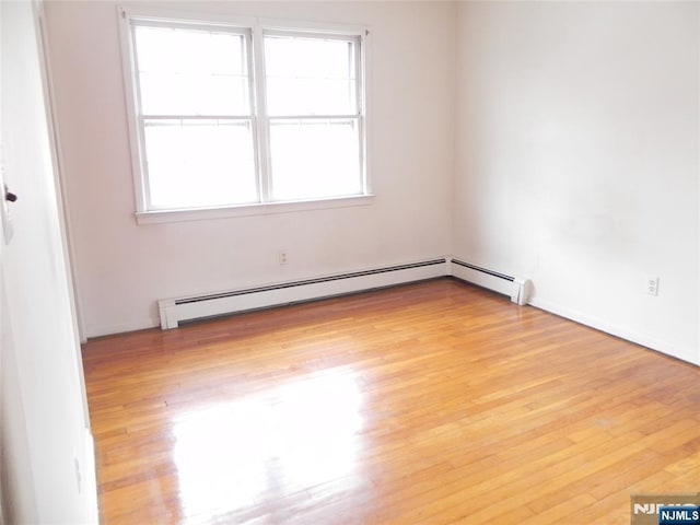 unfurnished room featuring a baseboard heating unit and light wood-type flooring