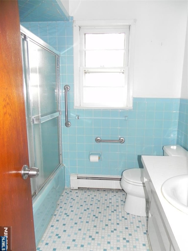 full bathroom featuring a baseboard heating unit, toilet, vanity, shower / bath combination with glass door, and tile walls