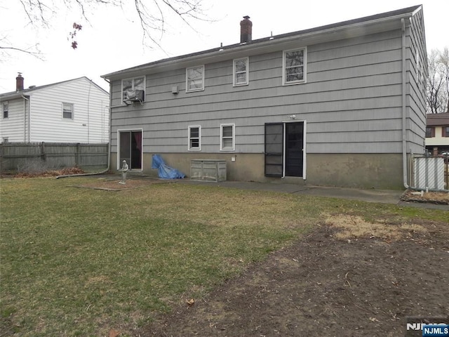 rear view of house with a lawn, cooling unit, a chimney, and fence