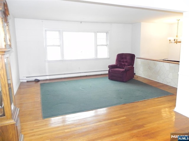 unfurnished room featuring a baseboard heating unit, wood finished floors, and a chandelier