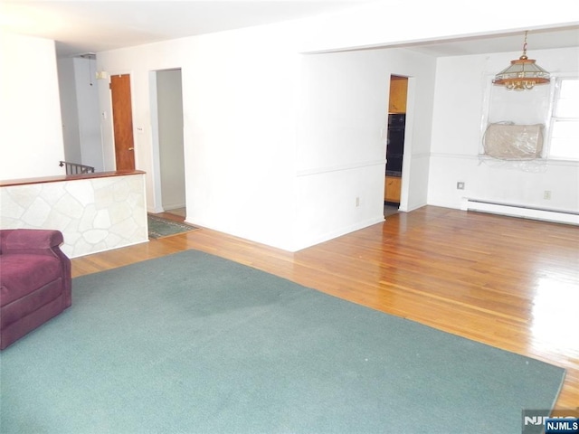 unfurnished living room featuring a baseboard radiator and wood finished floors