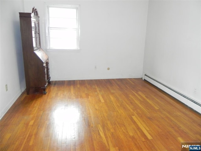 unfurnished room featuring wood finished floors and baseboard heating