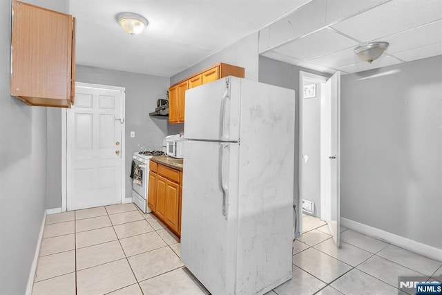 kitchen with light tile patterned flooring, white appliances, and range hood