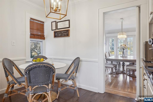 dining area with a chandelier, dark wood-type flooring, a wealth of natural light, and wainscoting