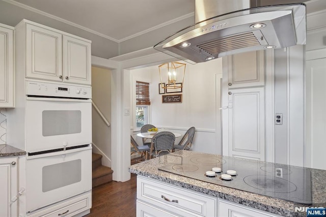 kitchen featuring dark stone counters, double oven, island exhaust hood, and black electric cooktop