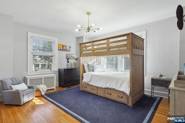 bedroom with a chandelier, baseboards, radiator heating unit, and wood finished floors