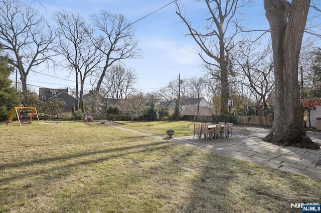 view of yard featuring a playground, fence, and a patio