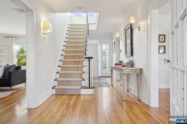 entryway with crown molding, a wealth of natural light, visible vents, and light wood-style floors