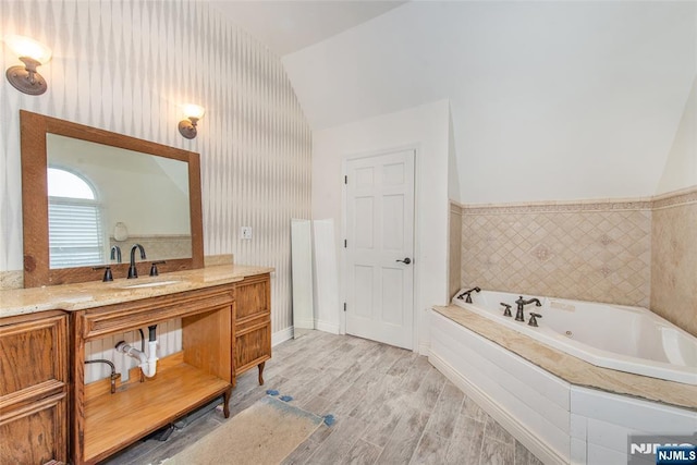 bathroom featuring a tub, lofted ceiling, hardwood / wood-style floors, and vanity