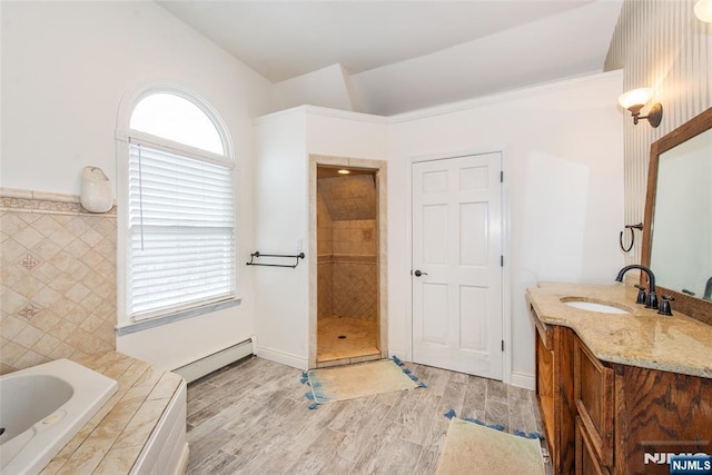 bathroom featuring hardwood / wood-style flooring, a healthy amount of sunlight, lofted ceiling, and a baseboard heating unit