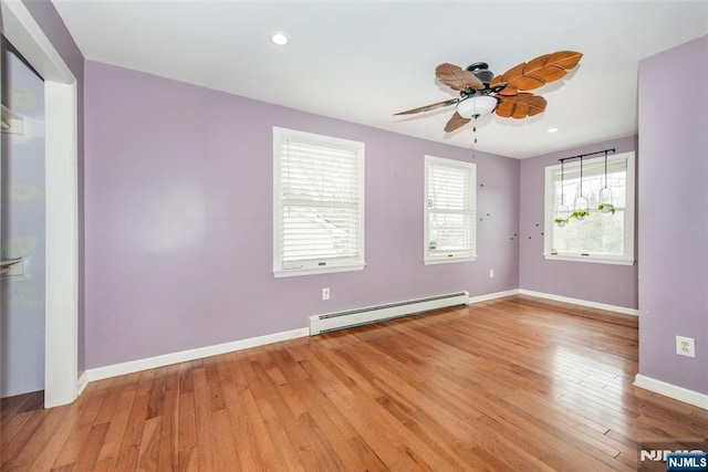 empty room featuring ceiling fan, wood-type flooring, and a baseboard heating unit