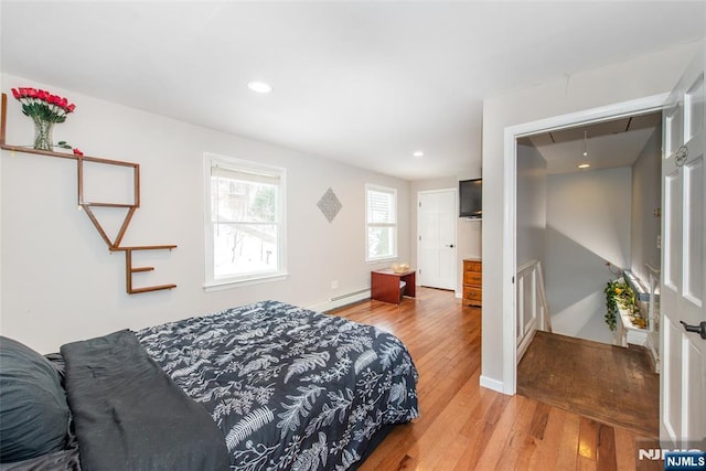 bedroom featuring a baseboard heating unit and light hardwood / wood-style floors