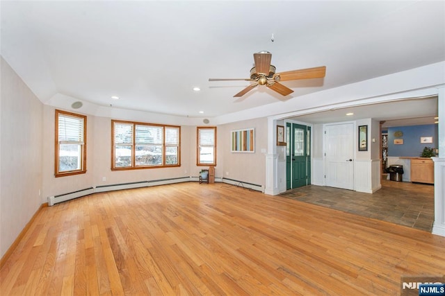 unfurnished living room with baseboard heating, light hardwood / wood-style flooring, and a wealth of natural light