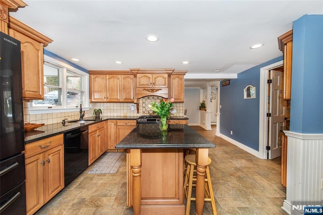 kitchen featuring sink, a kitchen island, tasteful backsplash, black appliances, and a kitchen bar