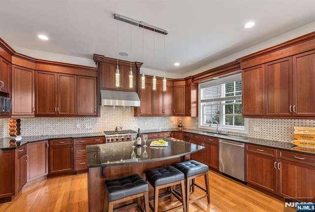 kitchen featuring a breakfast bar, ventilation hood, appliances with stainless steel finishes, a kitchen island, and pendant lighting