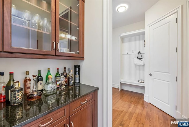 bar featuring light hardwood / wood-style floors and dark stone counters