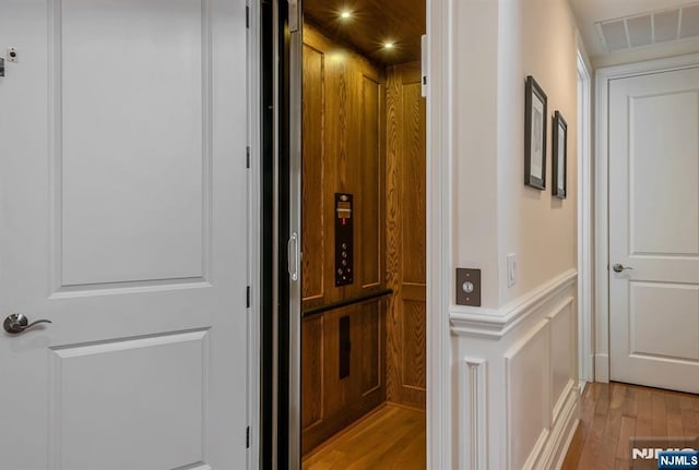 hallway with elevator and light hardwood / wood-style floors